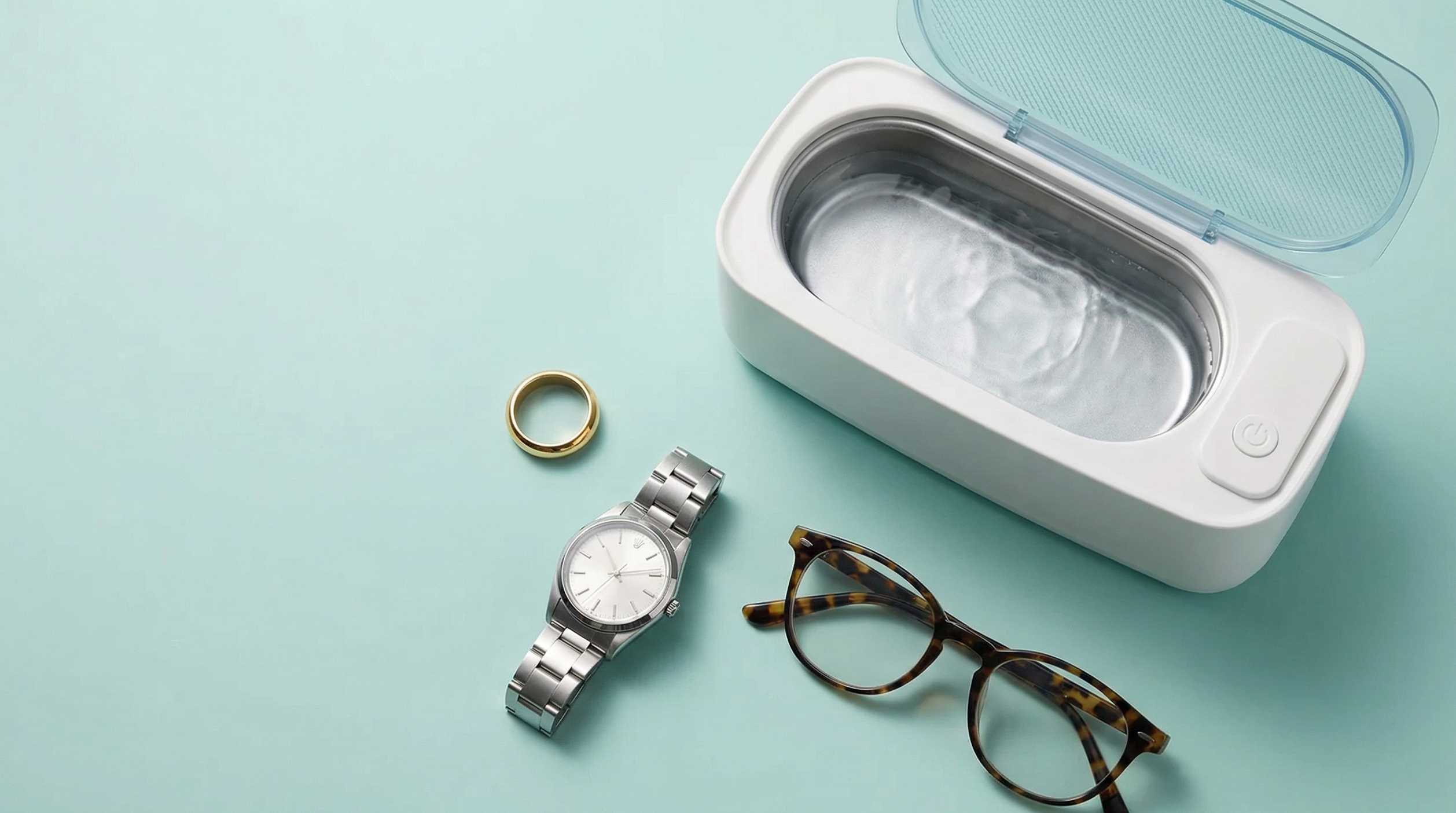 Cleaning device with a watch, glasses, and ring on a light blue background